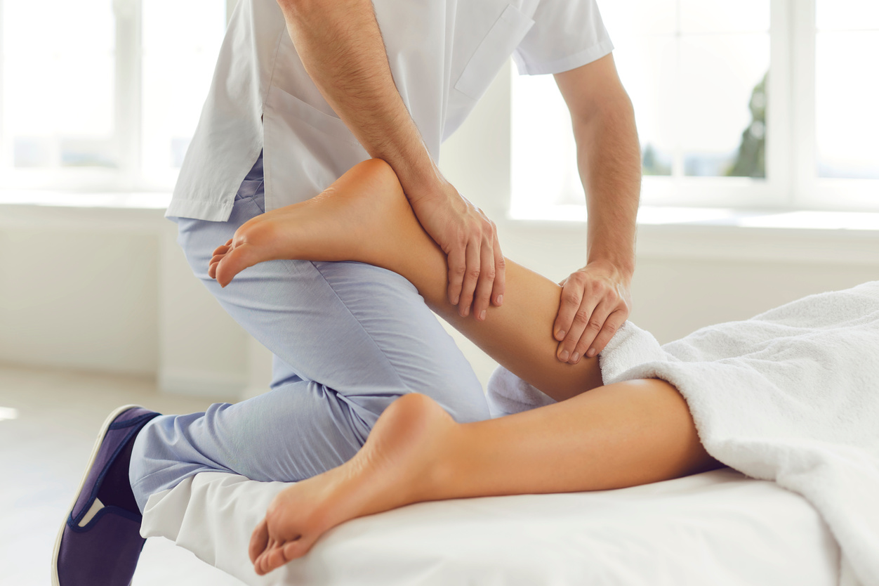 Physiotherapist or Reflexologist Massaging Young Woman's Calf Muscle in Wellness Center